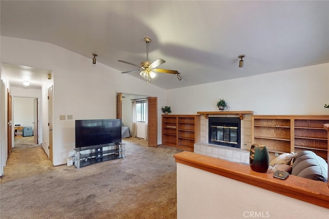 carpeted living room featuring ceiling fan, lofted ceiling, and a tile fireplace