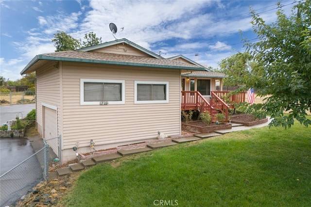 back of house with a wooden deck, a garage, and a lawn