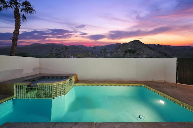 pool at dusk featuring an in ground hot tub and a mountain view