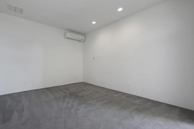 unfurnished room with an AC wall unit and dark colored carpet