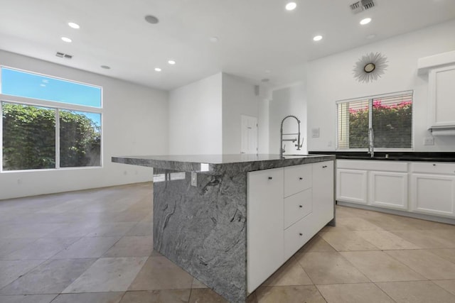 kitchen with a center island, sink, white cabinets, and light tile patterned floors