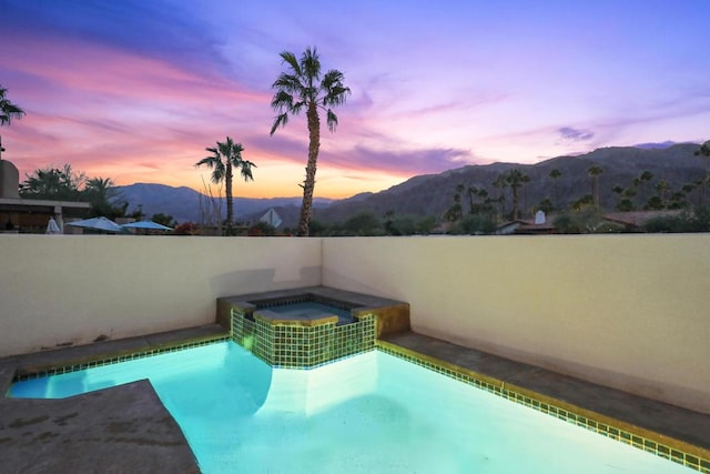 pool at dusk with a mountain view and an in ground hot tub