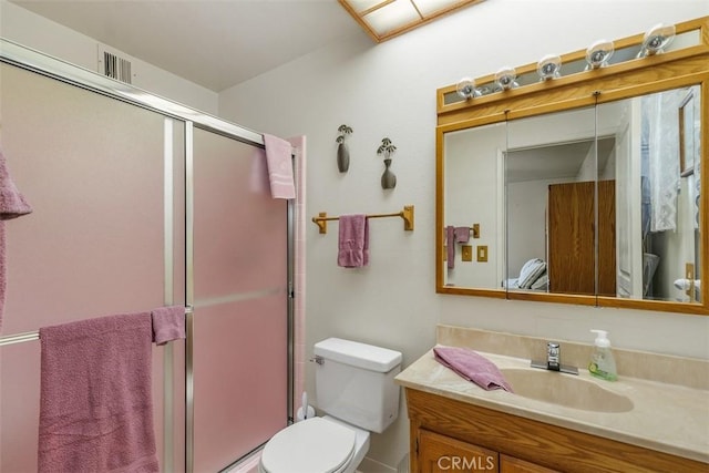 bathroom featuring vanity, a shower with shower door, and toilet