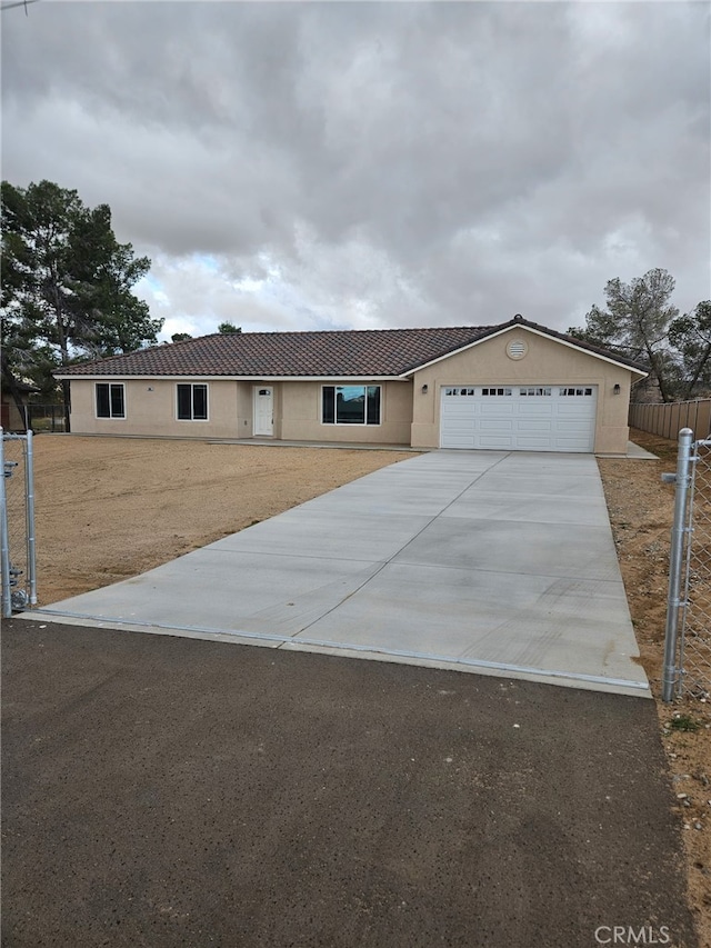 ranch-style house featuring fence, a tiled roof, concrete driveway, stucco siding, and an attached garage