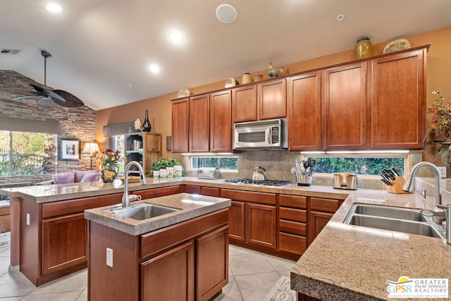 kitchen with sink, kitchen peninsula, appliances with stainless steel finishes, and a kitchen island with sink