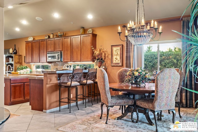 kitchen with decorative light fixtures, tasteful backsplash, a chandelier, light tile patterned floors, and a breakfast bar area