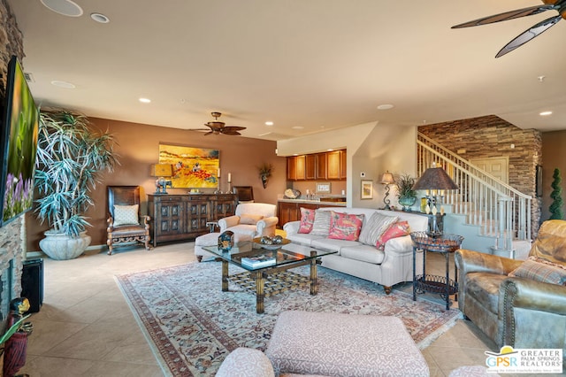 living room featuring ceiling fan, light tile patterned floors, and a stone fireplace