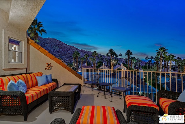 patio terrace at dusk with a mountain view, a balcony, and an outdoor hangout area