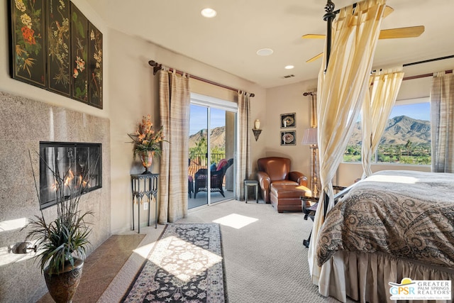 carpeted bedroom featuring a fireplace, a mountain view, and access to outside