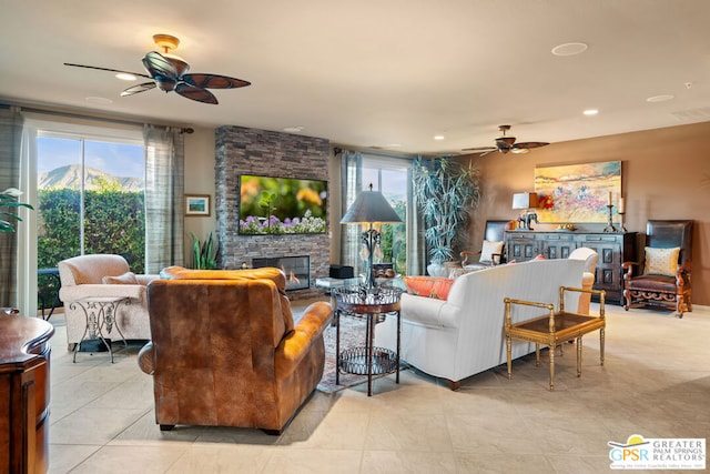 living room with a fireplace, light tile patterned floors, and ceiling fan