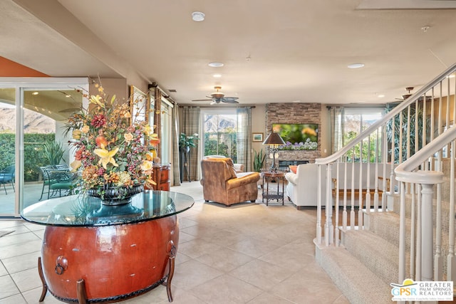 living room featuring ceiling fan, light tile patterned flooring, and a healthy amount of sunlight