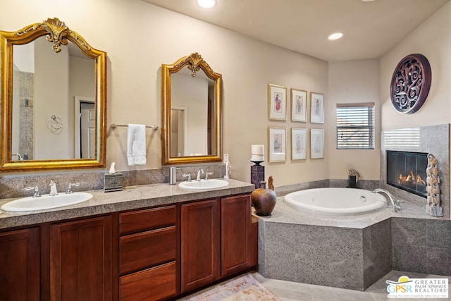 bathroom with a relaxing tiled tub, tile patterned floors, and vanity