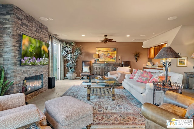 living room with ceiling fan, light tile patterned floors, and a stone fireplace