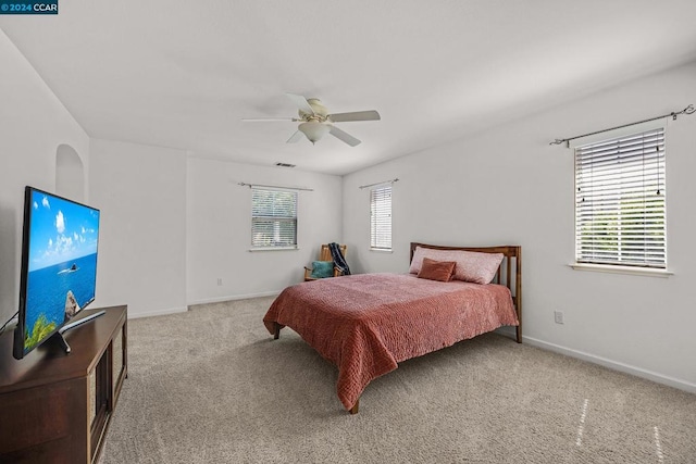 bedroom with ceiling fan, multiple windows, and light colored carpet