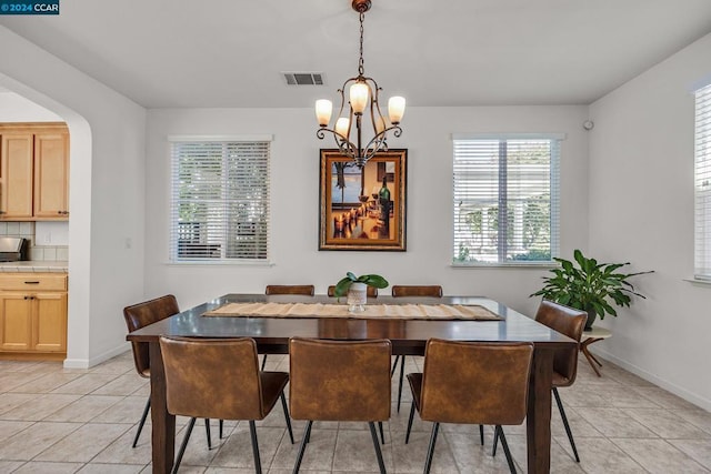 tiled dining room with a notable chandelier