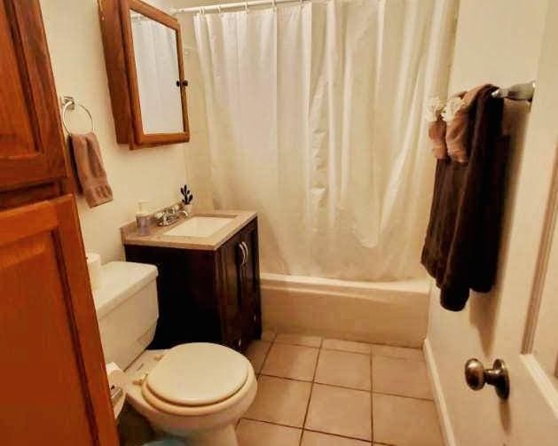 full bathroom with toilet, vanity, tile patterned floors, and shower / bathtub combination with curtain