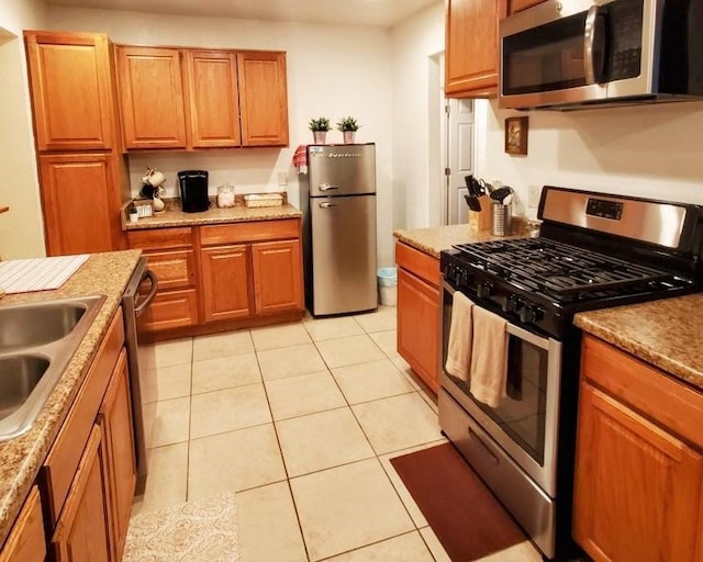 kitchen with light stone countertops, sink, light tile patterned floors, and appliances with stainless steel finishes