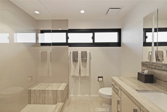 bathroom with vanity, toilet, and tiled shower