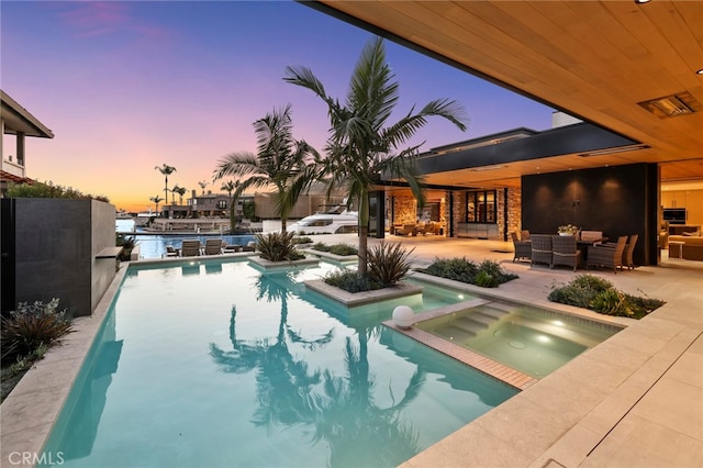 pool at dusk with an in ground hot tub, an outdoor living space, and a patio