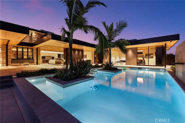 pool at dusk featuring a patio area