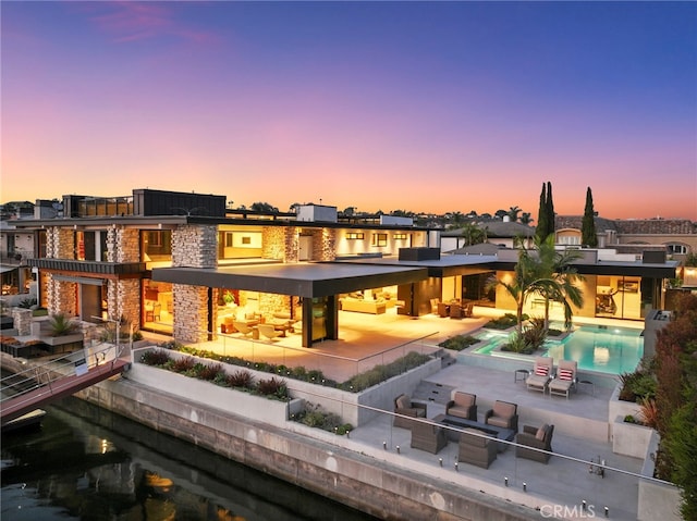 back house at dusk featuring a patio area