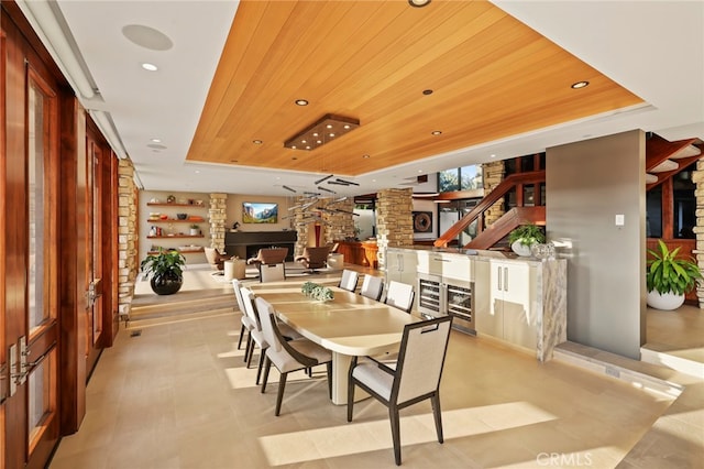 dining room with a fireplace, a tray ceiling, and wooden ceiling