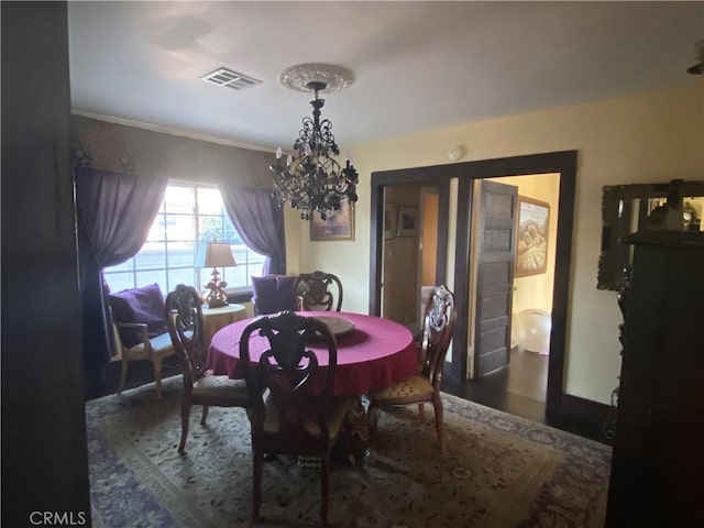 dining space with dark hardwood / wood-style floors, crown molding, and a chandelier