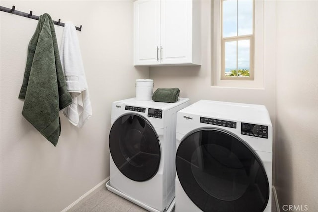 washroom with cabinets, washing machine and dryer, and light tile patterned flooring