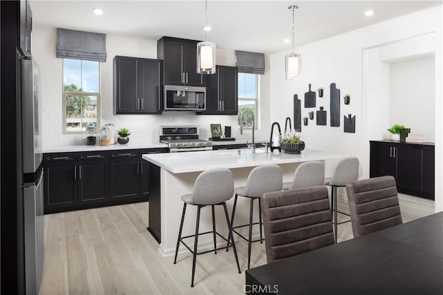 kitchen with appliances with stainless steel finishes, pendant lighting, a kitchen breakfast bar, and a healthy amount of sunlight