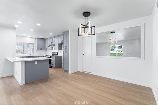 kitchen featuring electric range, light hardwood / wood-style flooring, hanging light fixtures, and a healthy amount of sunlight