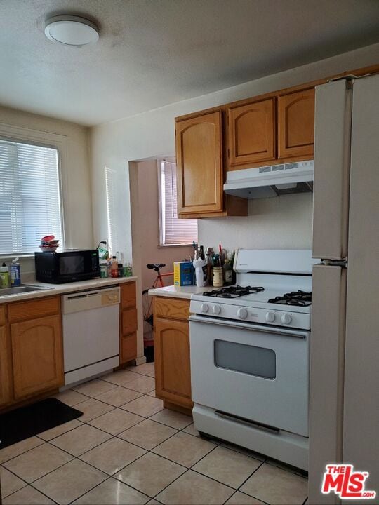 kitchen with light tile patterned flooring, white appliances, and sink