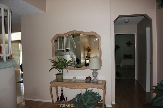 corridor with a textured ceiling, dark hardwood / wood-style floors, and water heater