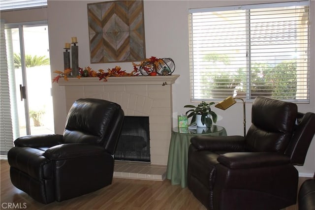 sitting room featuring wood-type flooring, a healthy amount of sunlight, and a tiled fireplace