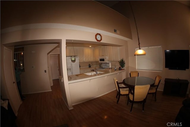 kitchen with white cabinetry, dark wood-type flooring, kitchen peninsula, white appliances, and decorative light fixtures