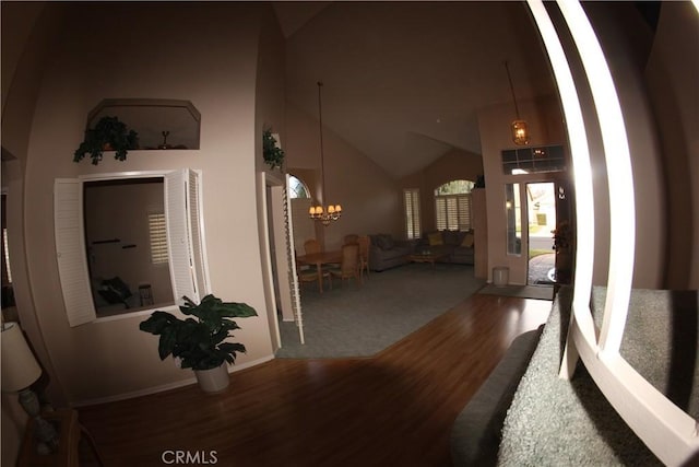 hall featuring wood-type flooring, high vaulted ceiling, and a chandelier