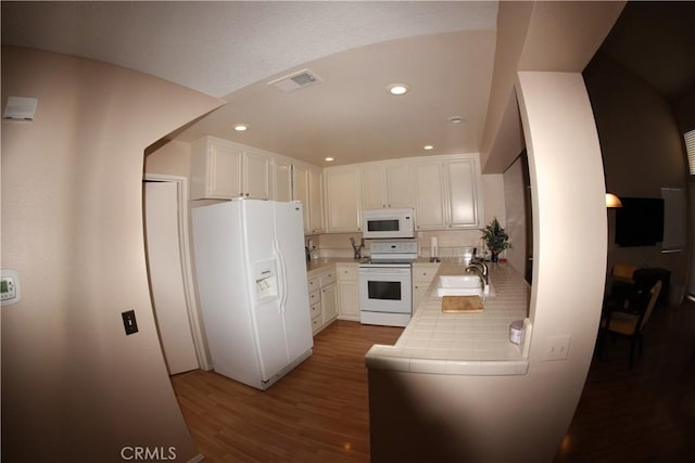 kitchen with white cabinetry, tile counters, sink, wood-type flooring, and white appliances