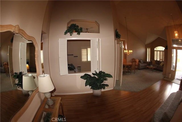 corridor featuring hardwood / wood-style flooring, high vaulted ceiling, and a notable chandelier