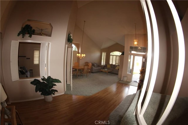 dining area with high vaulted ceiling, ceiling fan with notable chandelier, and hardwood / wood-style flooring