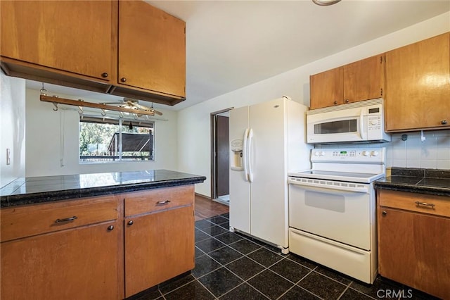 kitchen with white appliances, tasteful backsplash, and dark stone countertops