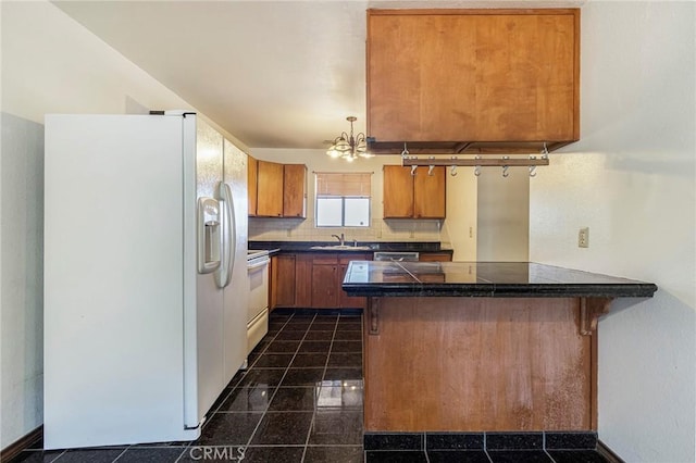 kitchen featuring sink, an inviting chandelier, a kitchen breakfast bar, kitchen peninsula, and white appliances