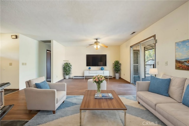 living room featuring hardwood / wood-style flooring, ceiling fan, and baseboard heating