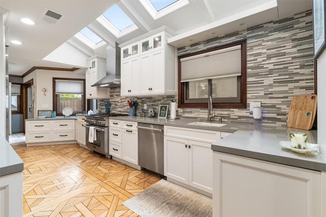 kitchen featuring wall chimney exhaust hood, white cabinets, stainless steel appliances, and backsplash