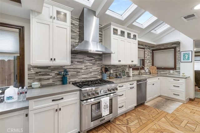 kitchen featuring sink, wall chimney exhaust hood, appliances with stainless steel finishes, and white cabinets