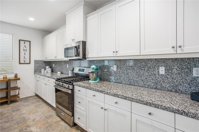 kitchen with decorative backsplash, light stone countertops, white cabinets, and stainless steel appliances