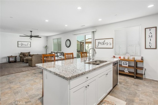 kitchen with white cabinetry, sink, ceiling fan, and a center island with sink