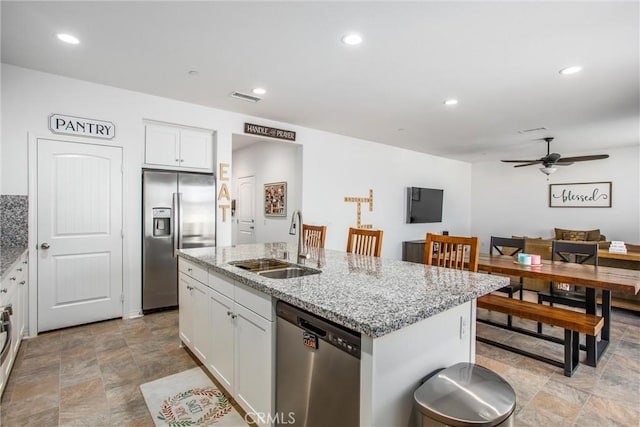 kitchen with ceiling fan, sink, stainless steel appliances, a center island with sink, and white cabinets