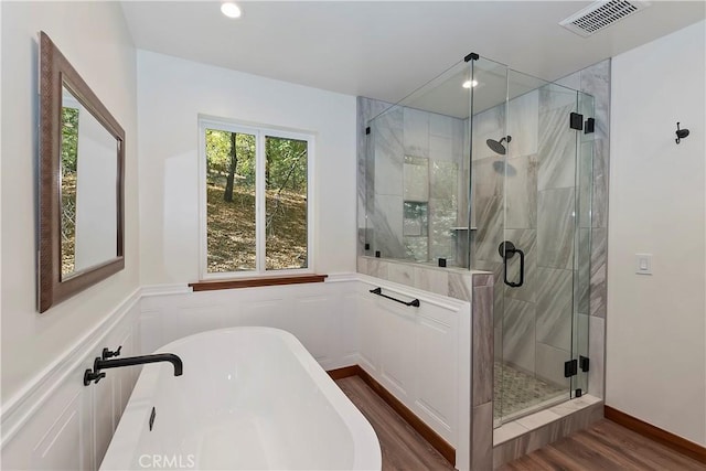 bathroom with independent shower and bath and wood-type flooring