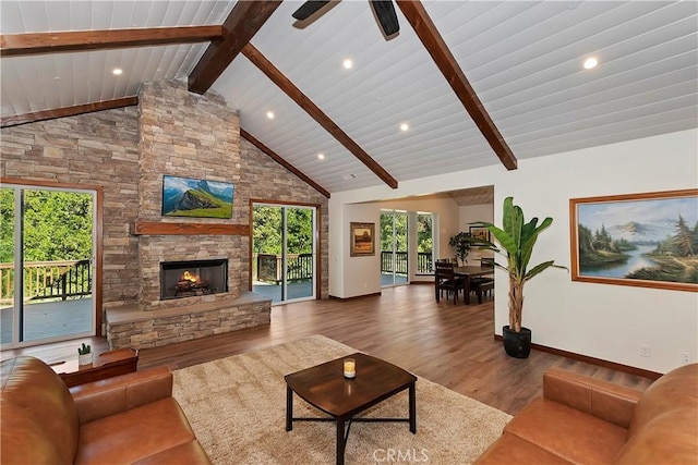 living room with ceiling fan, a stone fireplace, beamed ceiling, high vaulted ceiling, and wood-type flooring