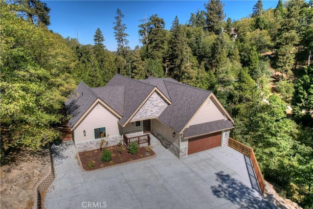 1285 N State Highway 173, Lake Arrowhead, CA 92352 - view of front of property featuring stone siding, a garage, driveway, a wooded view, and covered porch
