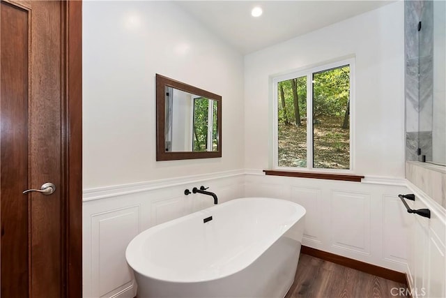 bathroom with a washtub and hardwood / wood-style flooring